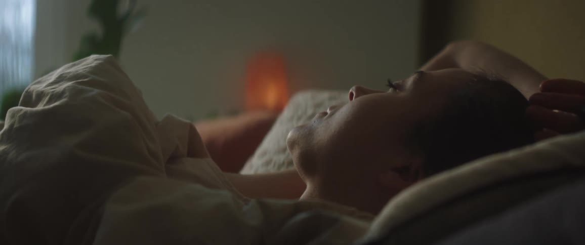 A close up of a woman laying in bed before she gets up and pulls the blankets off her