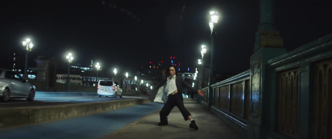 A woman dancing on a bridge in london at night