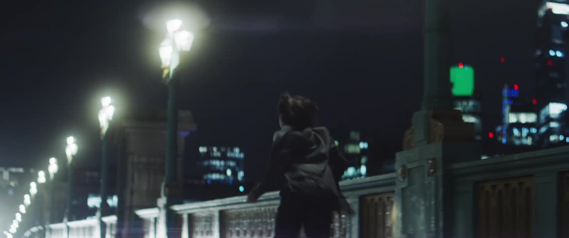 A woman moving and dancing down a bridge sidewalk spinning around