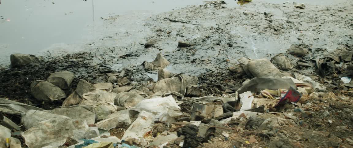 A dry river bed filled with garbage and mud