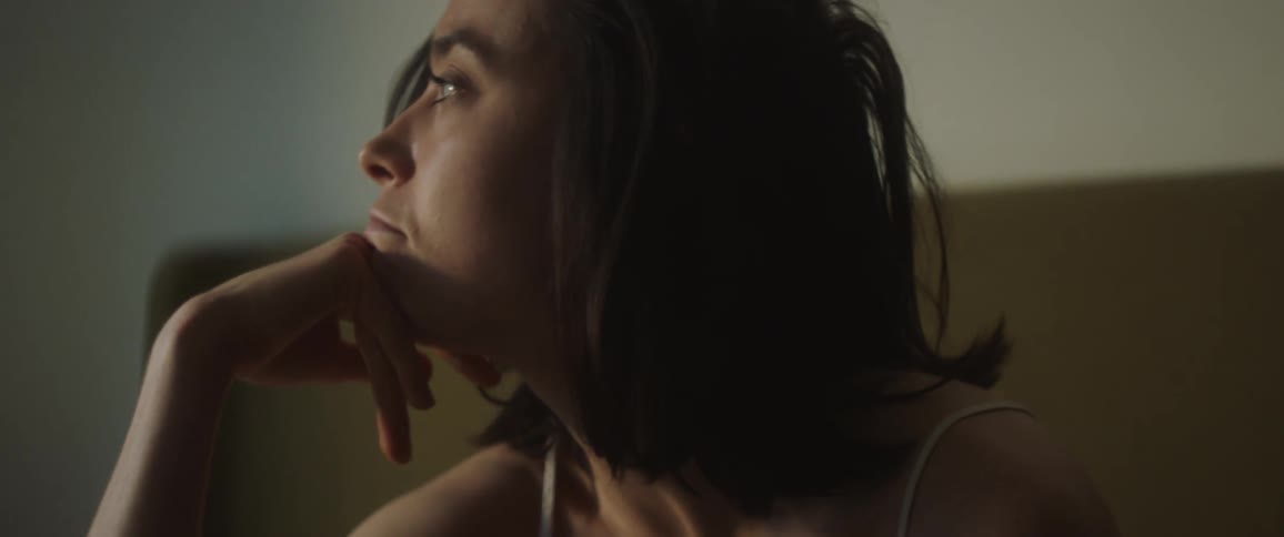A woman is sitting and brushes her hair back