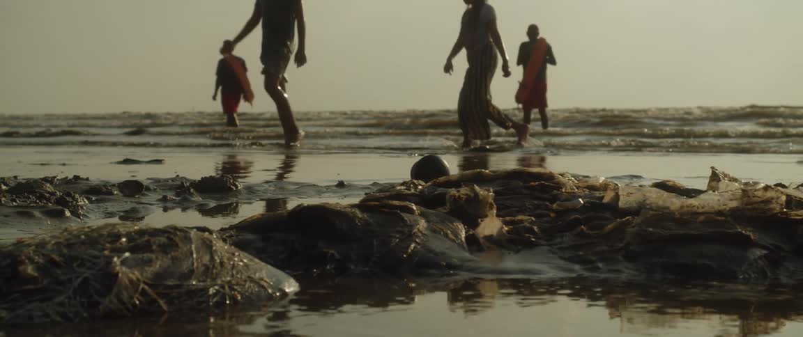 People are walking in the water on the polluted beach