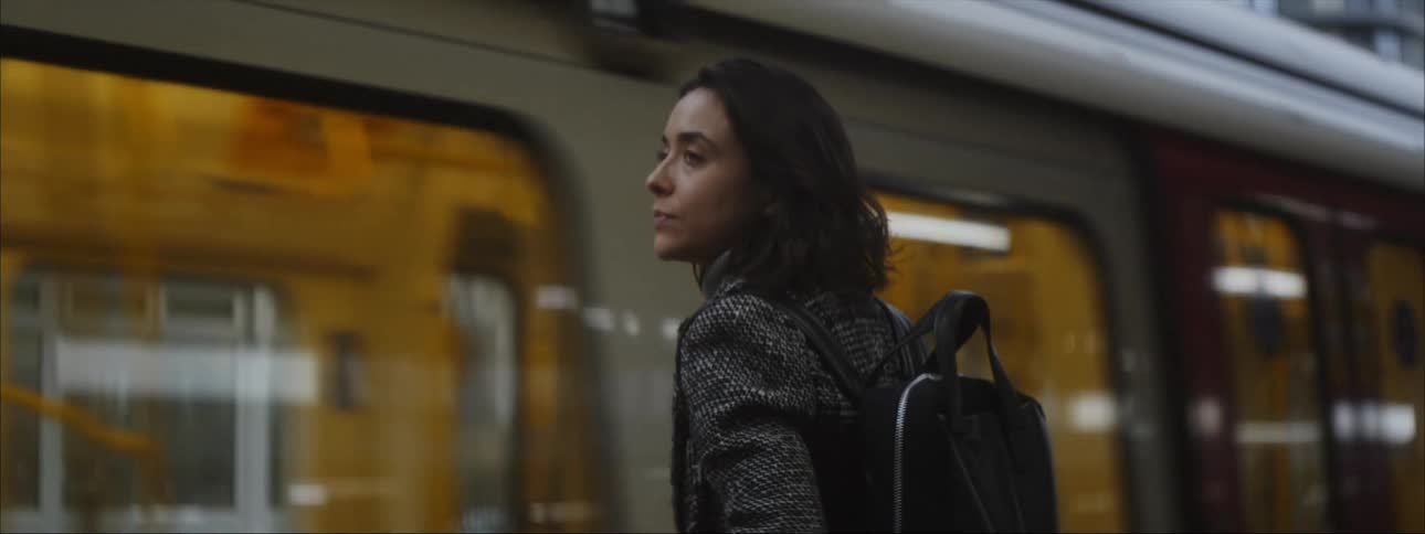 Woman waits on stopping metro as pedestrians cross behind her