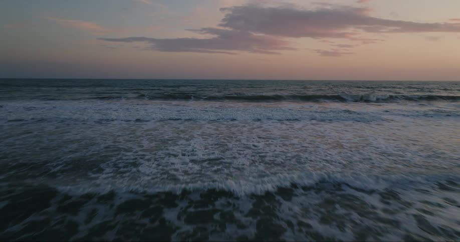 Waves rippling towards a beach at dusk