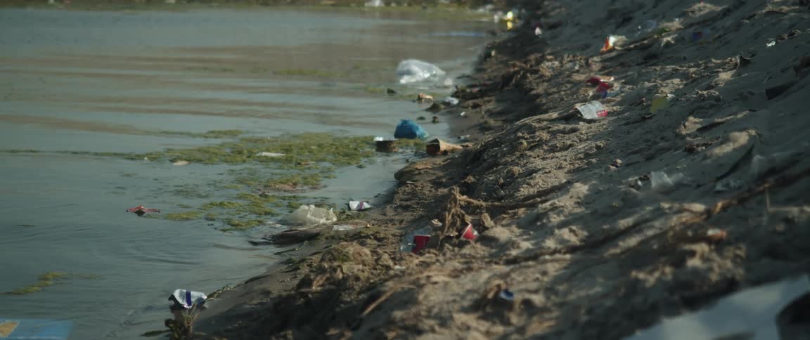 Water along a bank side with garbage on the land and in the water