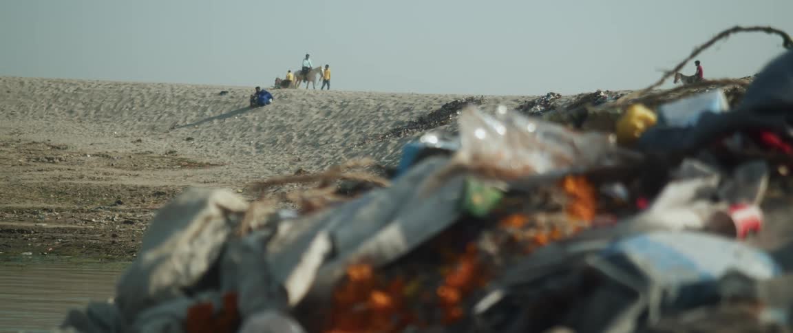 People on horses stand on a hill overlooking a landfill