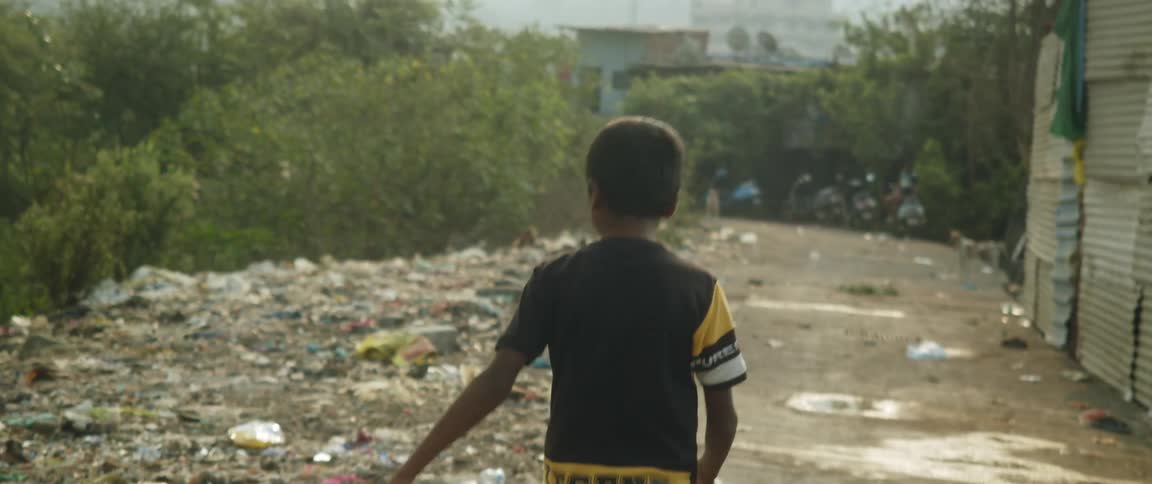 Youth walks past building and ground strewn with litter