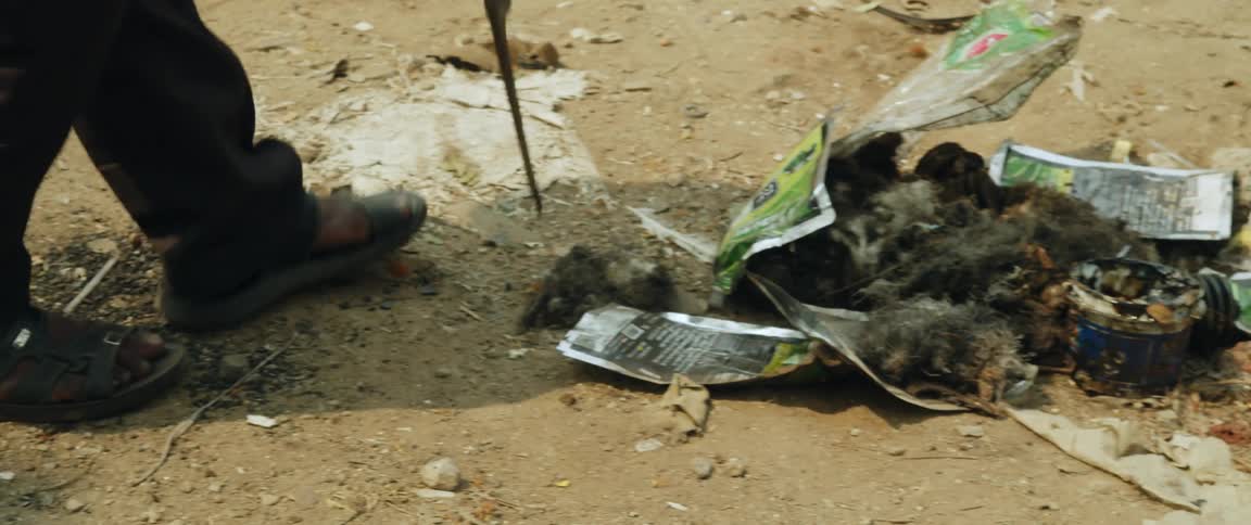 A person using a stick to gather garbage on the ground
