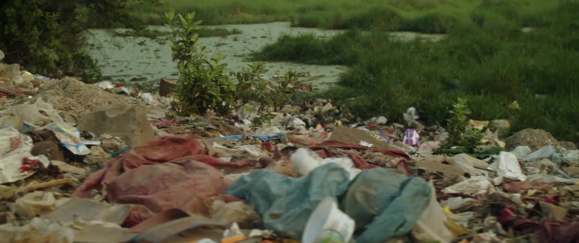 A large amount of trash and waste covering a big area in a grass field