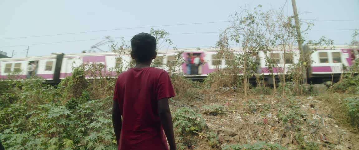 Boy with red t shirt watches train running