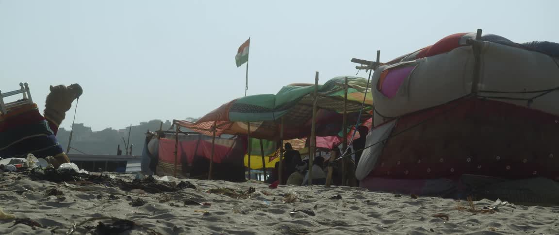 Flag waves over a homeless tent city on the beach near the city at daytime