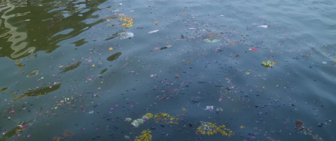 Sunlight reflects on the ripples in the water as trash and debris float on the surface