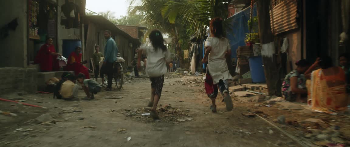 Two young girls running on the street of a slum at morning