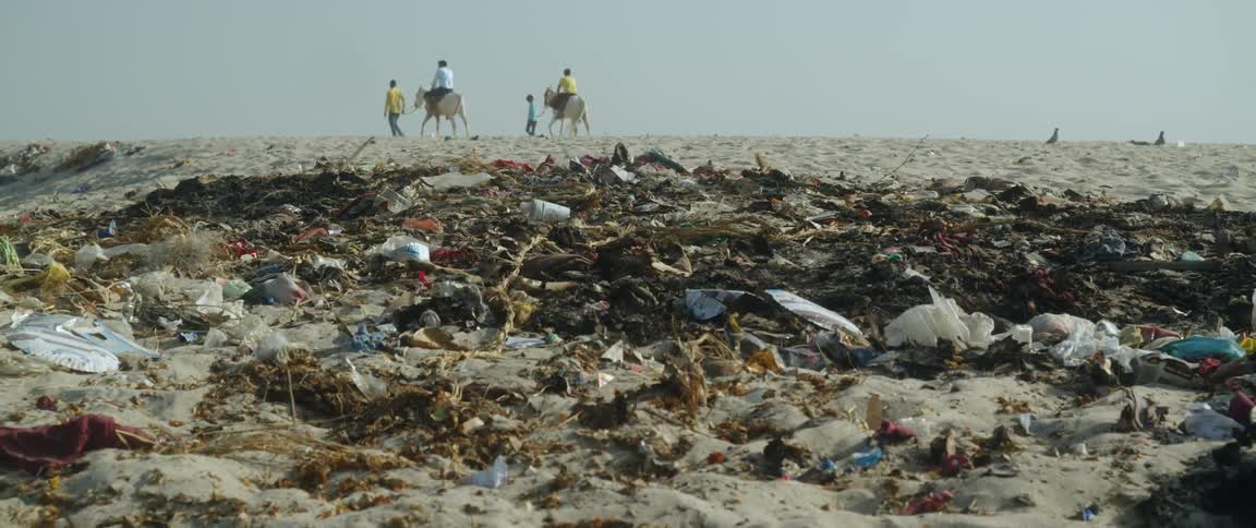 Four people crossing over a landfill two of them riding horses