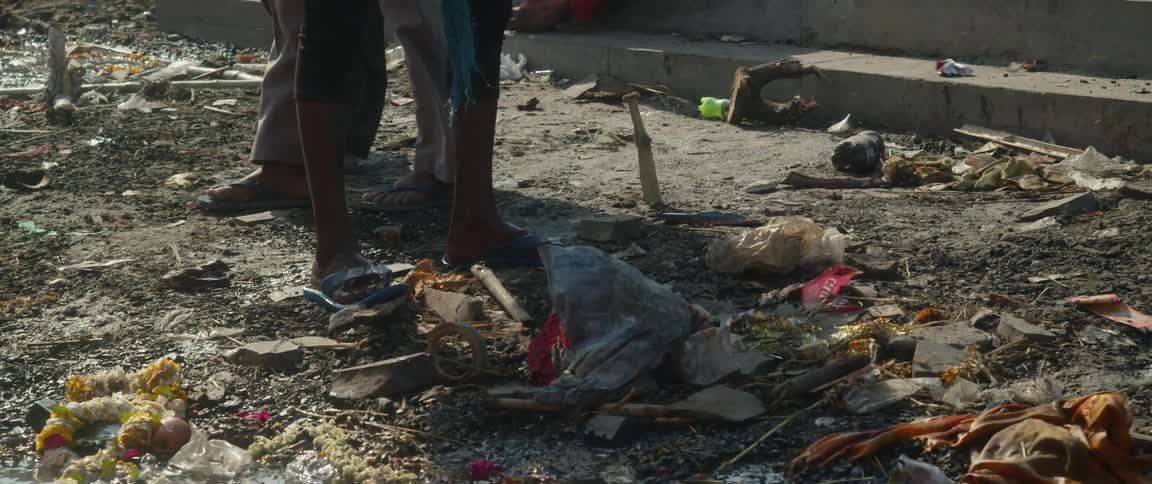 Three people walking around outside examining trash strewn about on the ground
