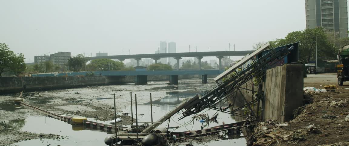 An improvised walkway over a dry river bed in a city
