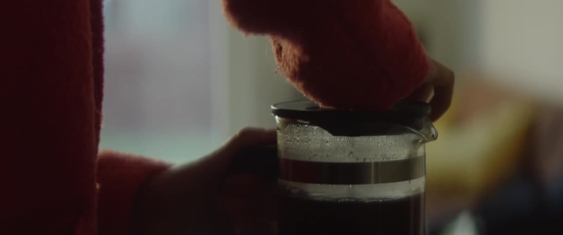 Silhouette of a person pumping a french coffee press at home