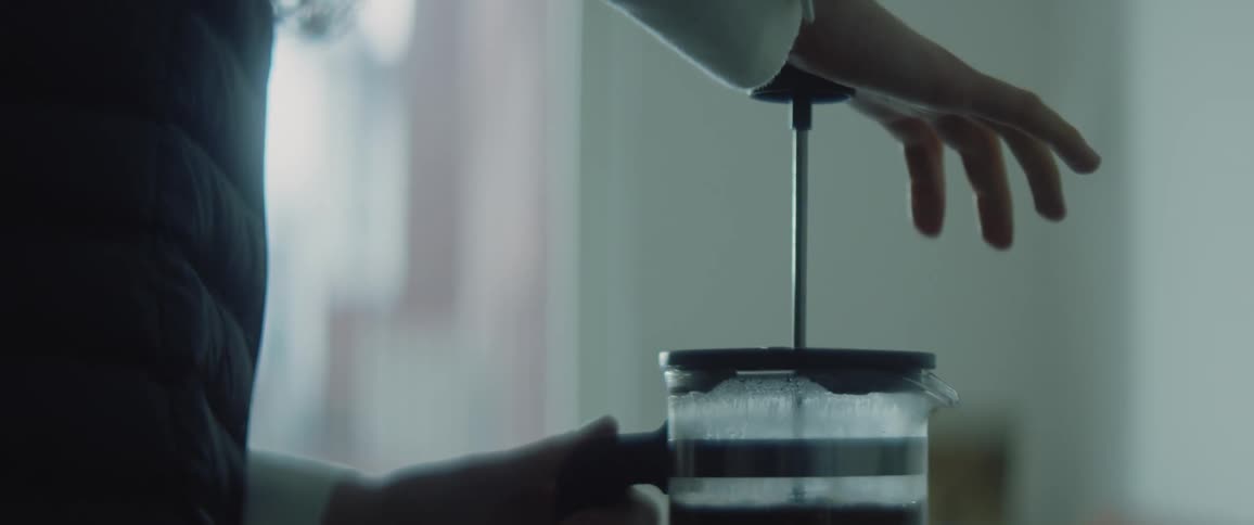 Silhouette of a person pumping a french press coffee maker at home