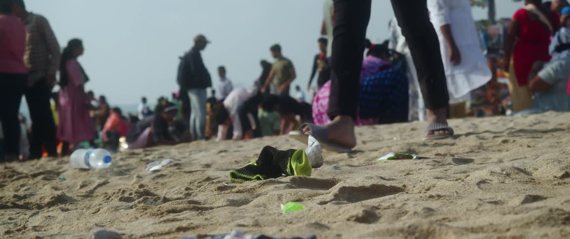 Person kicks up sand while walking away from crowd