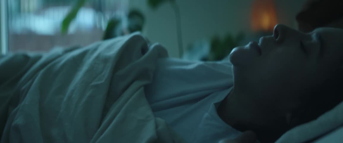 Woman with white shirt tries to wake up in her bed