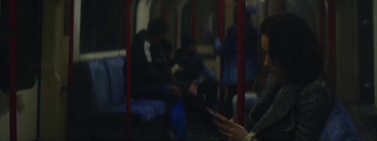 A woman scrolls through her phone while sitting on a train
