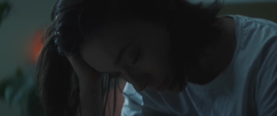 Woman rubs her head before sitting with her chin on her hand