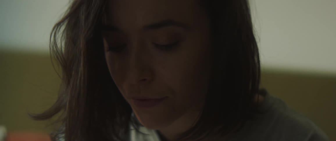 Woman with dark wavy hair looks down