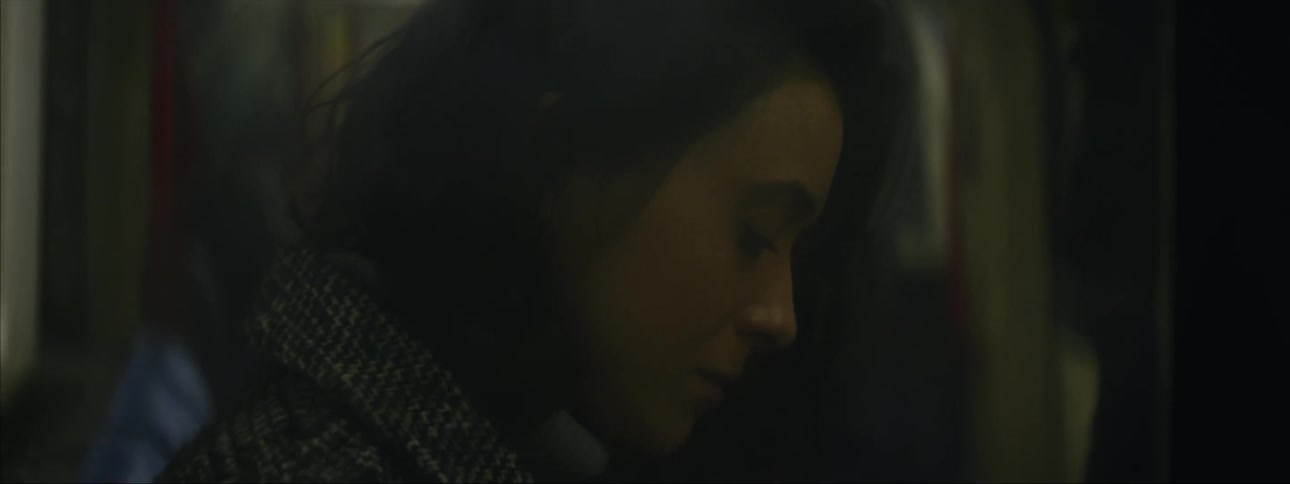 Woman wearing coat and sitting on public transportation briefly looks up