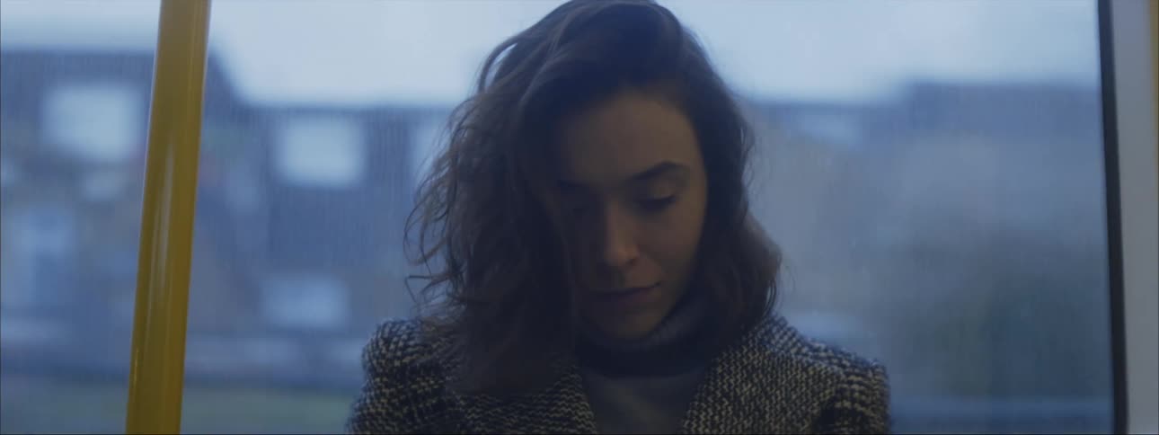 Close up of the face of a young woman sitting in a train moving through the city