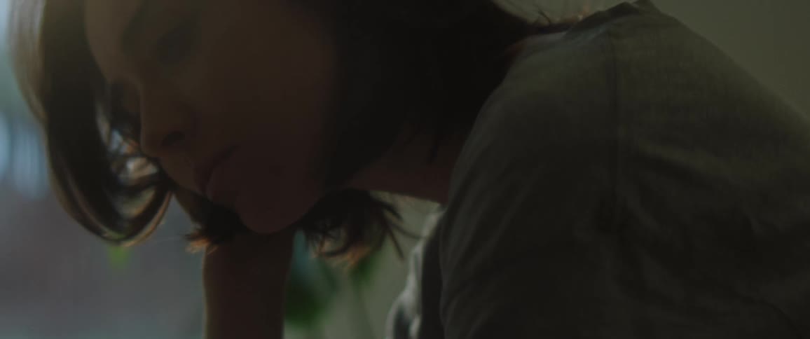 The view is of a young woman is sitting down and is yawning
