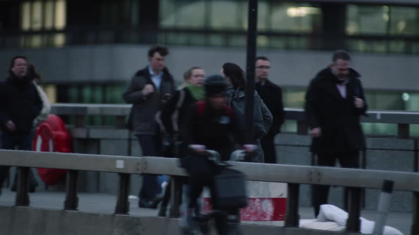 Woman with long overcoat and black backpack runs across the bridge