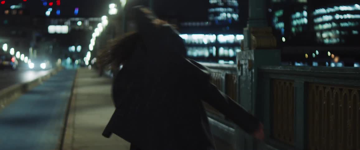 Woman dancing around chaotically on a bridge sidewalk near a city