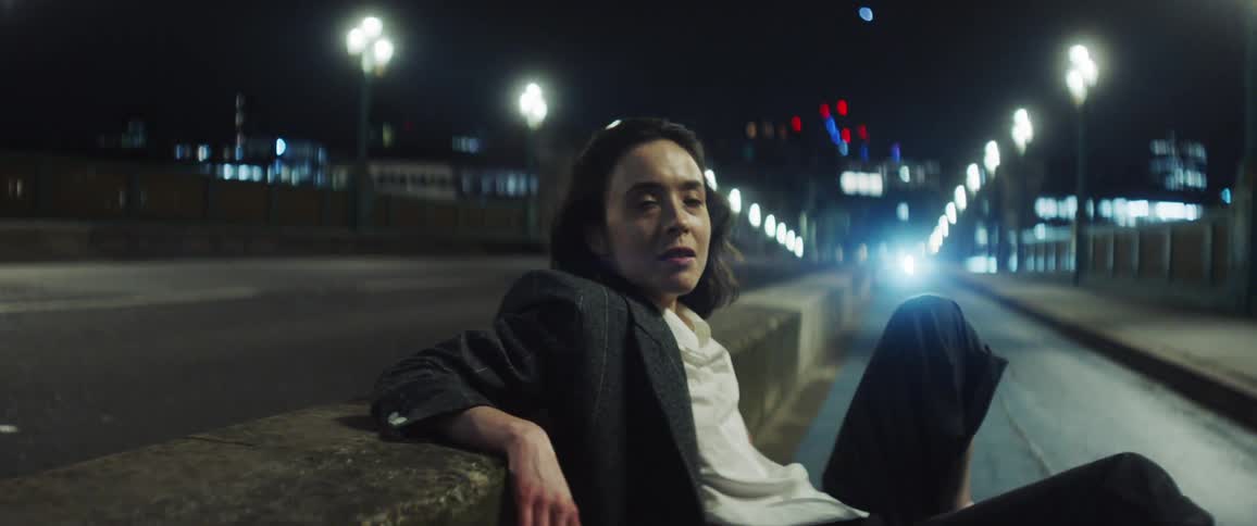 A woman is sitting down on a busy highway at night