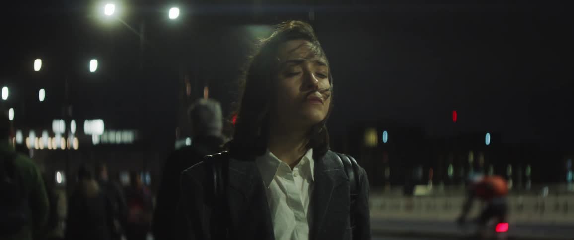 The view is of a young woman that is outside at night time