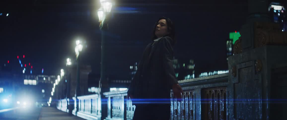 A woman standing on a bridge sidewalk slowly moving around and dancing