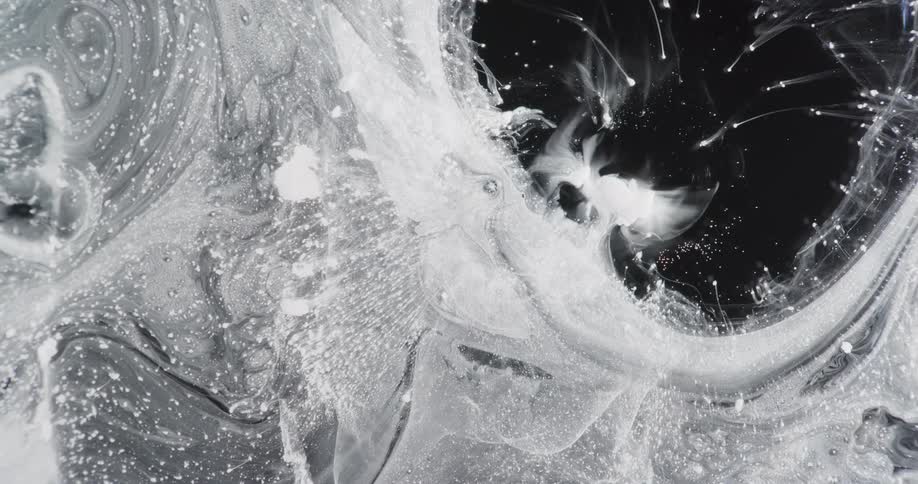White flows and streaks through expanding black with bubbles