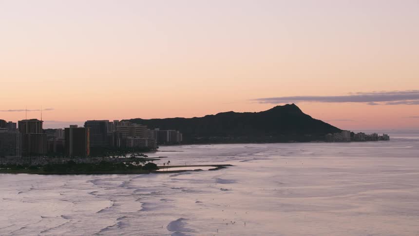 Two islands next to each other at dawn one with a city another with a mountain