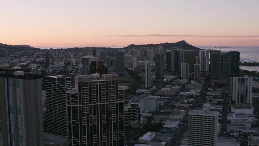 A coastal city with a mountain range in the background at dawn