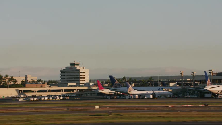 An airport runway leading to four parked airplanes and the terminal