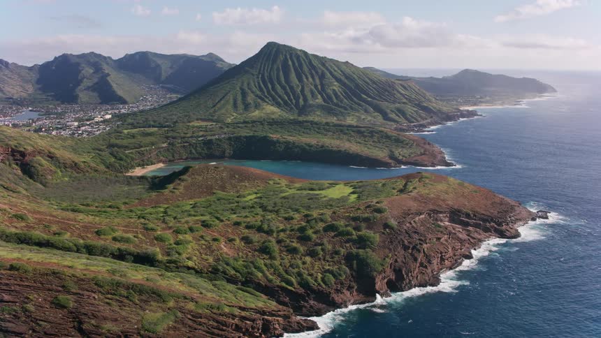 An aerial view of a mountainous coast reveals a bay with a beach
