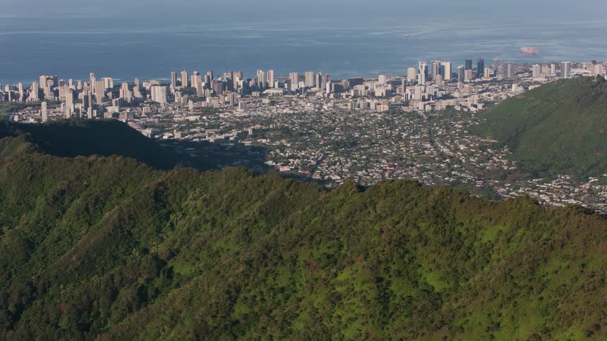 Drone view of mountain ridges with a metropolis city int eh valley along the coast