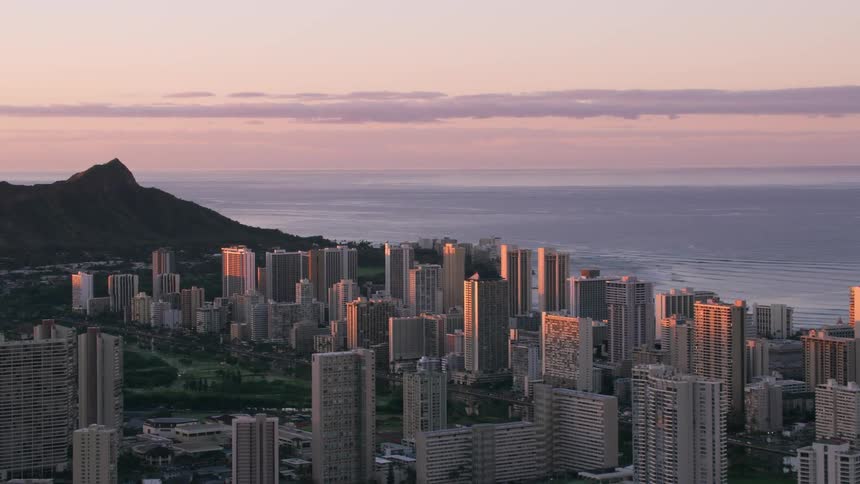 A coastal city at dawn with the sea and a mountain in the background