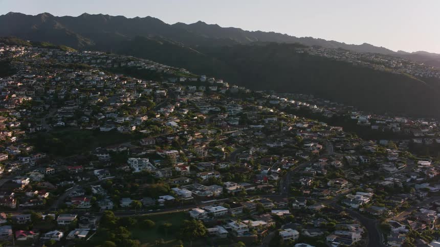 Drone view of a suburban neighborhood on a hillside among mountain ranges