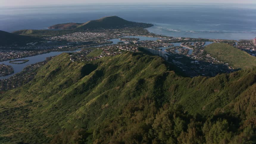 An aerial of a mountain range with towns built throughout and a metropolis cuity on the coast