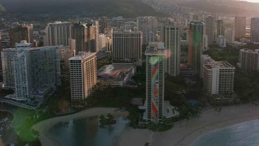 A coastal city with a large marina a beach and a mountain range in the background