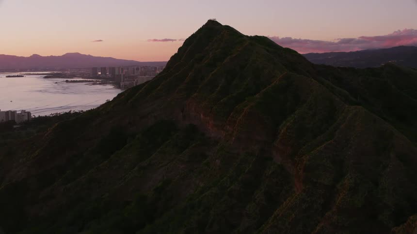Waves crash onto the shore below a cliff with views of downtown