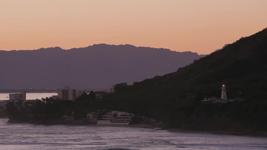 The sun is setting on the buildings by the shore
