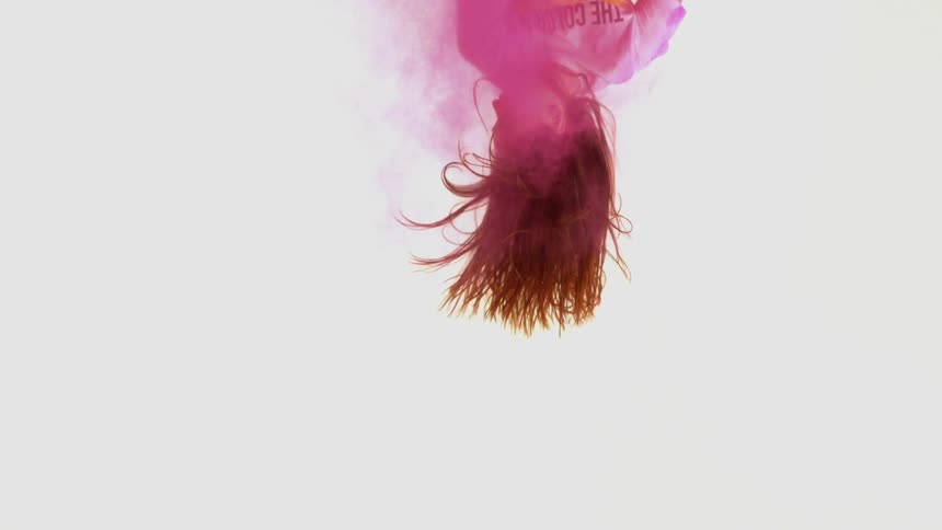 A woman flies through the air surrounded by pink powder