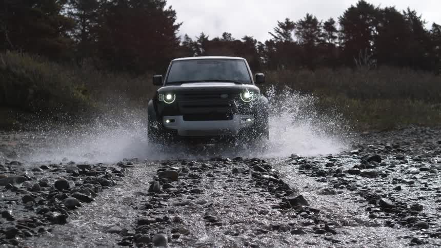 Black suv car drives through river splashing water