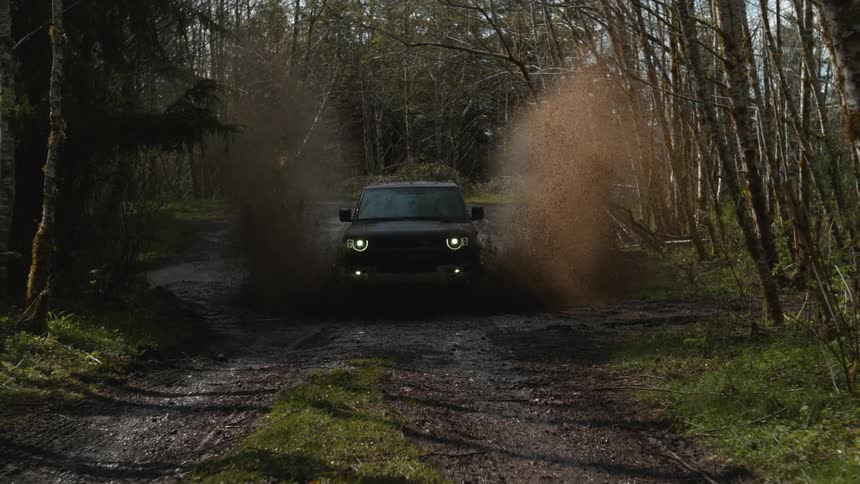The vehicle drives through a large puddle in the woods